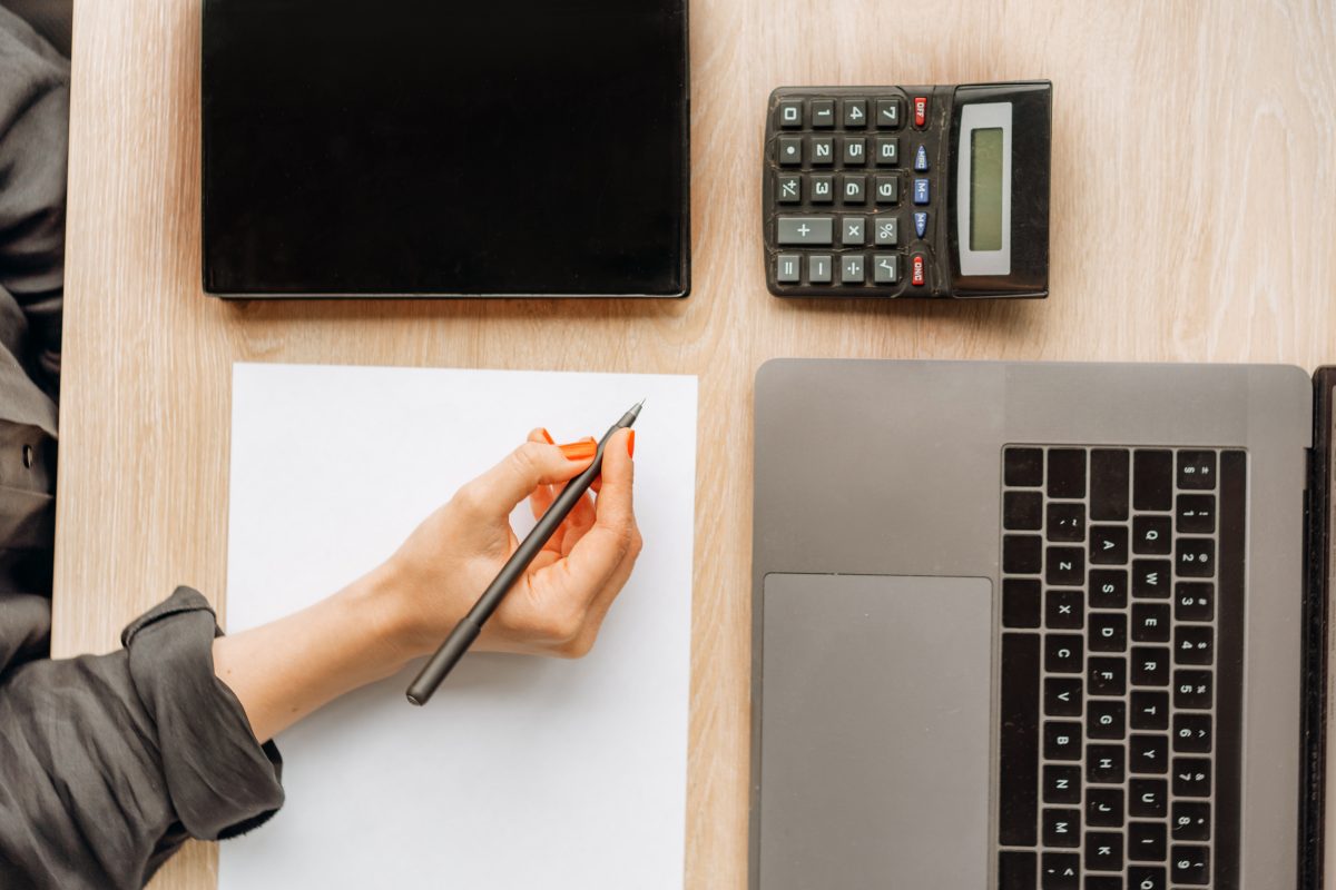 Arbeitsplatz mit Laptop, Taschenrechner und Unterlagen